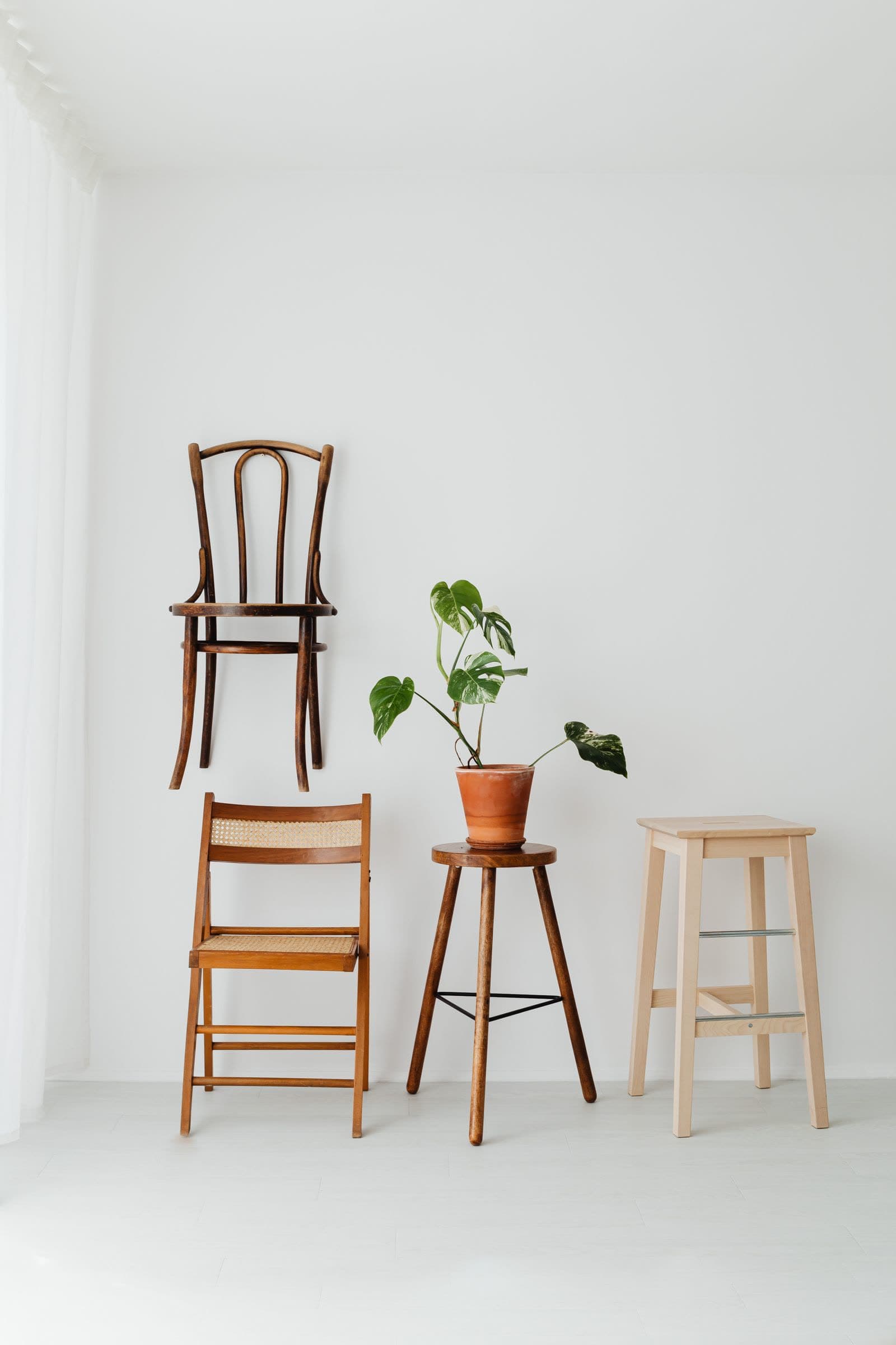 Stoelen en krukken uit de meubelmakerij, tegen een witte muur