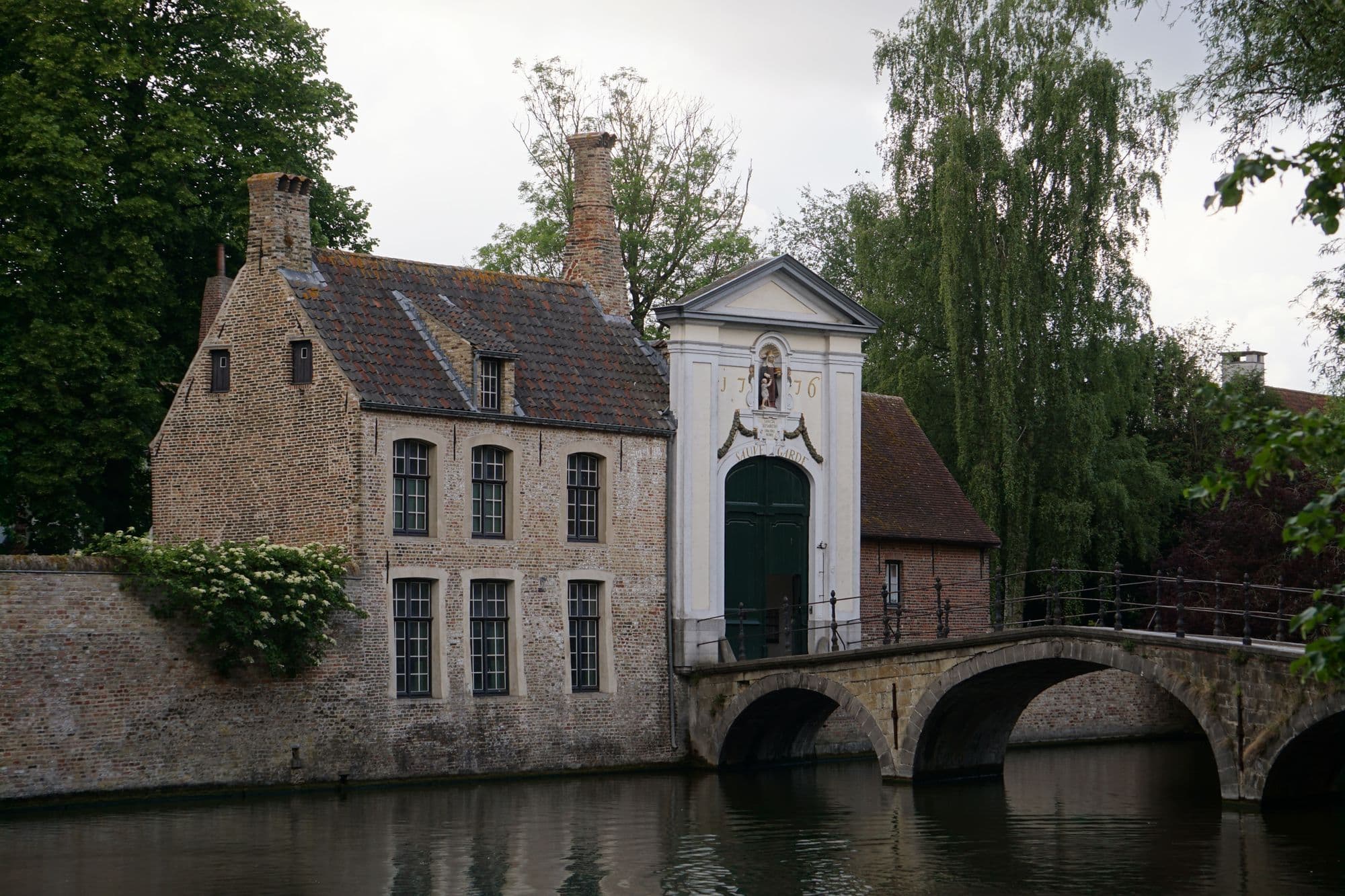 De stenen brug en de poort van het Begijnhof in Brugge, aan het water
