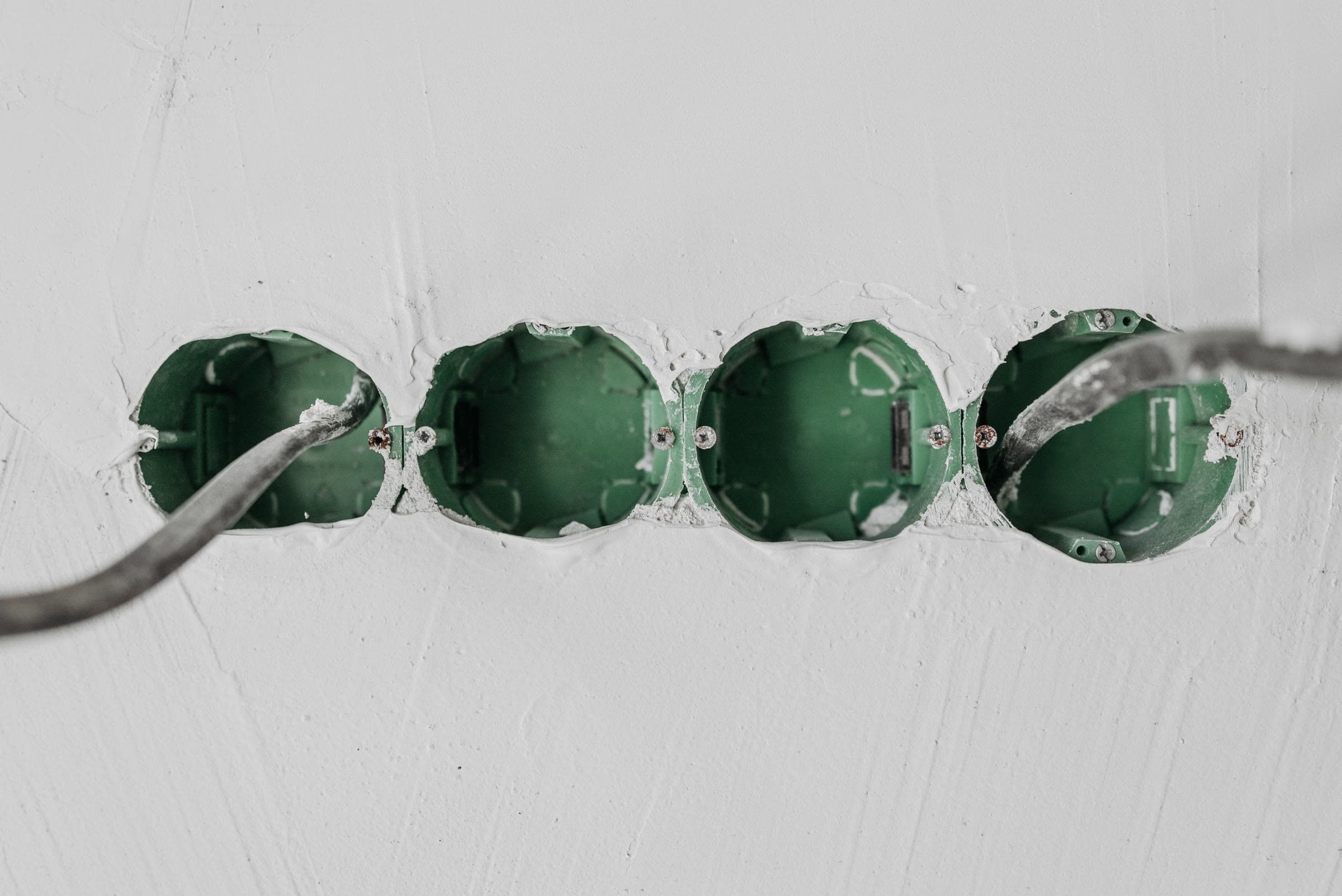 Groene inbouwdozen in een vers bepleisterde muur, met de kabels er al in